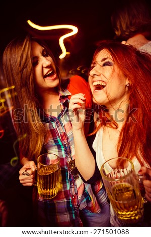 Girls having fun and drinking beer in night club