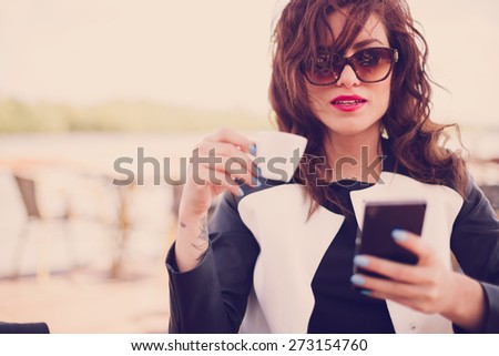 Young woman in cafe, drinking coffee and using her mobile phone