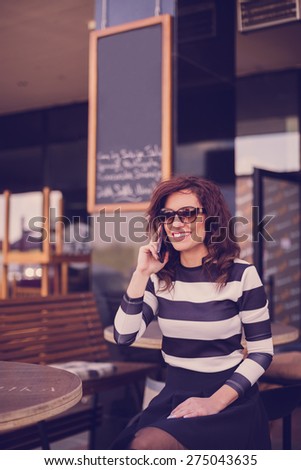 Young woman sitting at the bar and talking on the mobile phone