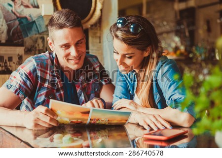 Happy couple sitting in cafe and looking at menu