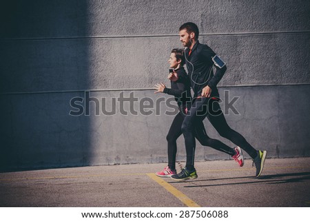 Side view of couple running in an urban environment