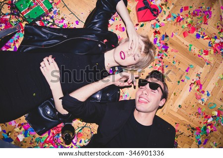 New Year\'s Party. Girl and boy laying on the floor full of confetti