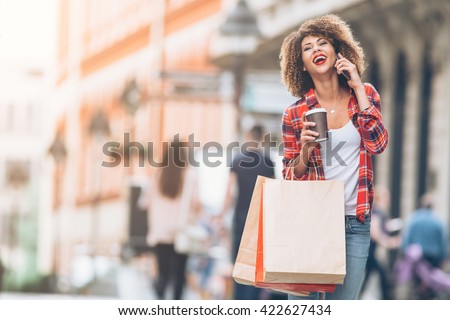 Young woman at the street with shopping bags talking on mobile phone