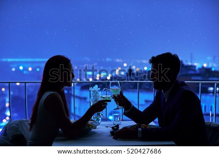 Young couple at restaurant having dinner. Silhouette