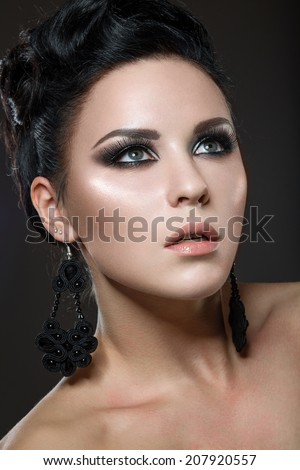 Beautiful brunette woman with perfect skin and handmade jewelry. Picture taken in the studio on a black background