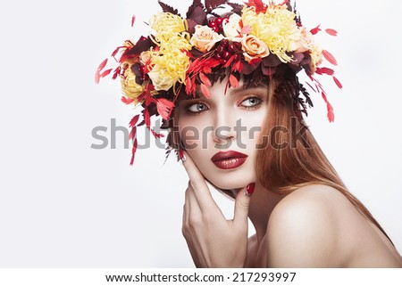 Beautiful red-haired girl with bright autumn wreath of leaves and flowers. Beauty face. Picture taken in the studio on a white background.