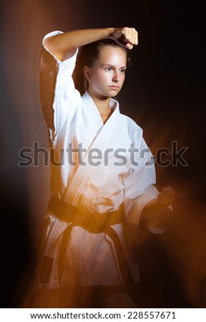 Young girl in a sports kimono in the image of judo. Picture taken in a studio with a mixed light on a gray background