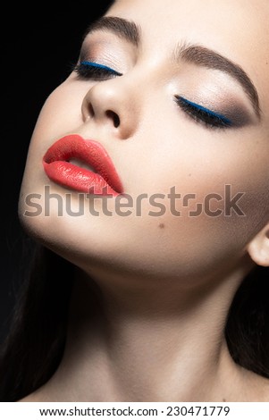 Beautiful woman with evening make-up and red lips. Beauty face. Picture taken in the studio on a black background.