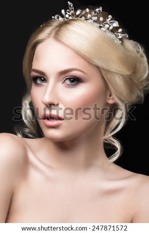 Beautiful blond girl in the image of a bride with a tiara in her hair. Picture taken in the studio on a black background. Beauty face. Wedding image.