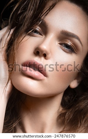 Beautiful young girl with a light natural make-up. Beauty face. Picture taken in the studio on a black background.