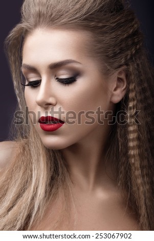 Beautiful woman with evening make-up, red lips and curls. Beauty face. Picture taken in the studio on a grey background.