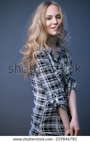 Beautiful blonde girl in a plaid shirt with a light make-up and loose hair. Model tests. Picture taken in the studio on a gray background.