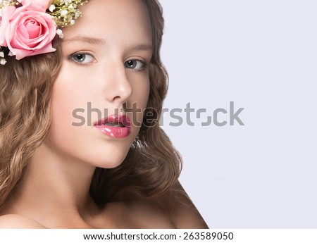 Beautiful girl with flowers in her hair and pink makeup. Spring image. Beauty face. Picture taken in the studio on a white background.
