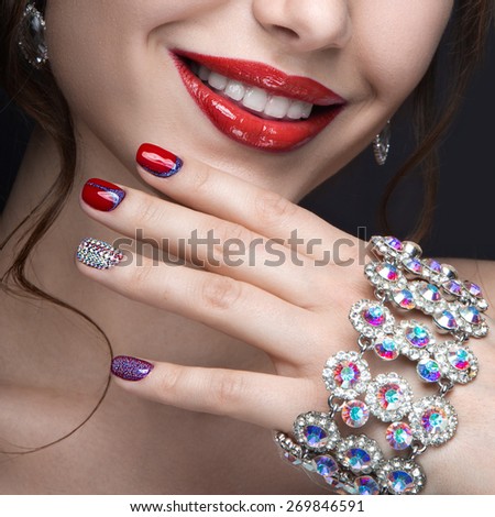 Beautiful girl with a bright evening make-up and red manicure with rhinestones. Nail design. Beauty face. Picture taken in the studio on a black background.