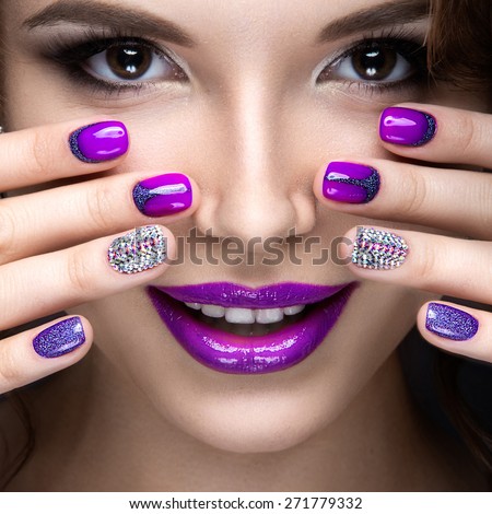 Beautiful girl with a bright evening make-up and purple manicure with rhinestones. Nail design. Beauty face. Picture taken in the studio on a black background.
