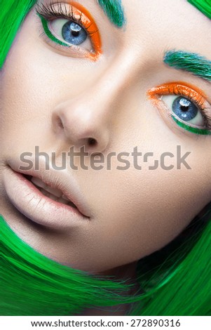Beautiful girl in a bright green wig in the style of cosplay and creative makeup. Beauty face. Art image. Picture taken in the studio on a yellow background.