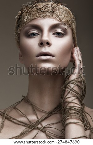 Beautiful girl with a bronze skin, pale makeup and unusual accessories. Art beauty image. Beauty face. Picture taken in the studio.