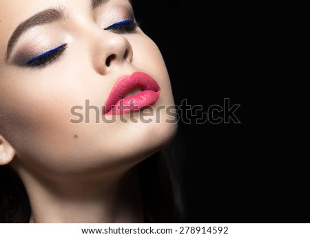 Beautiful woman with evening make-up and pink lips. Beauty face. Picture taken in the studio on a black background.