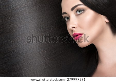 Beautiful brunette girl with a perfectly smooth hair and classic make-up. Beauty face. Picture taken in the studio on a white background.