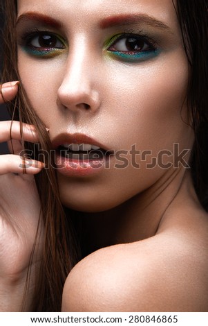 Beautiful girl with a bright colored makeup and wet hair and skin. Beauty face. Picture taken in the studio on a black background