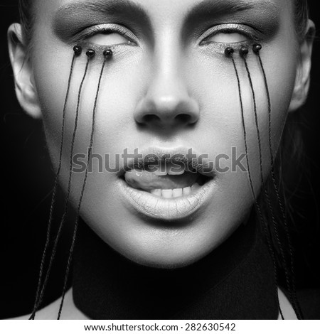 Beautiful girl with creative make-up in Gothic style and the threads of eyes. Art beauty face. Picture taken in the studio on a black background. Black and white photo