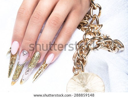 Beautiful long nails in a gold design with rhinestones. Nail art.