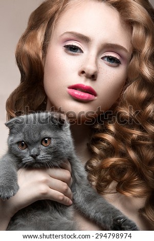 Beautiful young girl,  natural light makeup and curls with a cat in her arms. Beauty face.