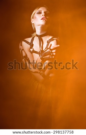 Beautiful fashionable woman in a leather sword belt and fire around. Art image.