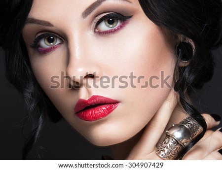 Beautiful Girl in the Gothic style with leather accessories and bright makeup. Beauty face. Picture taken in the studio on a black background.