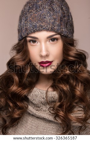 Beautiful girl with gentle makeup, curls in brown knit hat. Warm winter image. Beauty face.