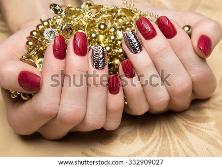 Beautiful red manicure with crystals on female hand. Close-up. Picture taken in the studio