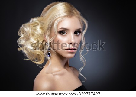 Beautiful blond girl in a black dress with evening haircut  form of waves and bright makeup. Beauty face.