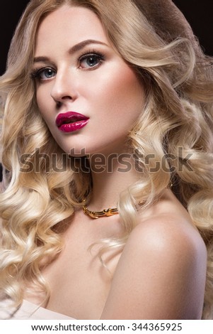 Beautiful blonde in a Hollywood manner with curls, red lips. Beauty face. Picture taken in the studio