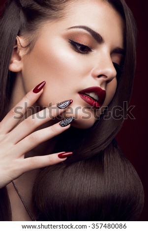 Pretty girl with unusual hairstyle, bright makeup, red lips and manicure design. Beauty face. Art nails.
