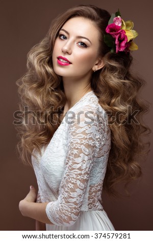 Beautiful blond woman in wedding dress with evening make-up, tender lips and curls. Bride image. Beauty face. Picture taken in the studio on a gray background