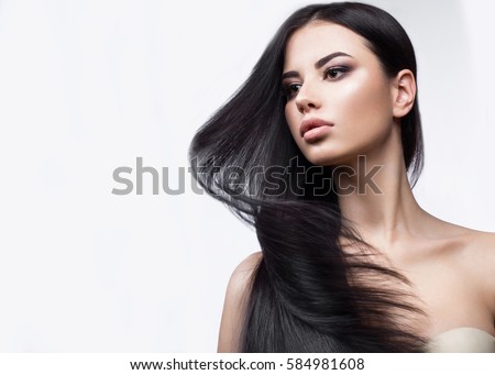 Beautiful brunette girl in move with a perfectly smooth hair, and classic make-up. Beauty face. Picture taken in the studio on a white background.