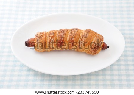 sausage roll bread on plate on table cloth