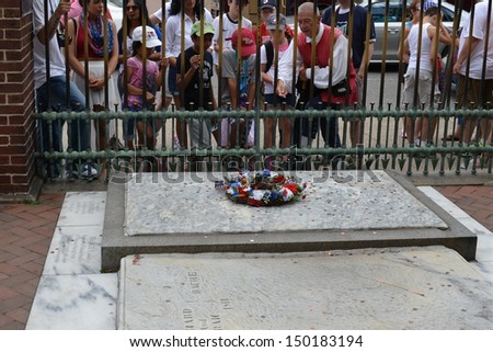PHILADELPHIA- JULY  4: Tourists gather to toss coins on Benjamin Franklin\'s grave during Independence Day Celebrations on July 4, 2013 in Philadelphia, PA.