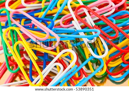 colored paper clips scattered heap closeup on a golden background