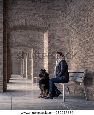 Young woman sitting on a bench with your best four-legged friend quietly peering into the camera. Architectural arch repeating in the background, with brick texture and marble floors.