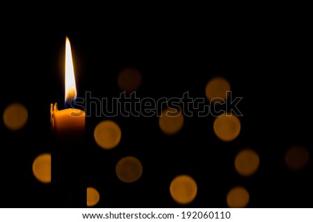 Yellow candle on the dark background and bokeh