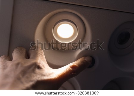 Passengers using the hand to turn off lights on the switch board on the plane.