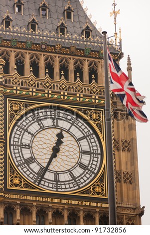 A close-up of the face of Big Ben, Westminster, with a Union Jack flag in the foreground
