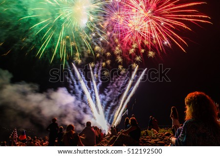 People sitting at the beach an watching the fireworks