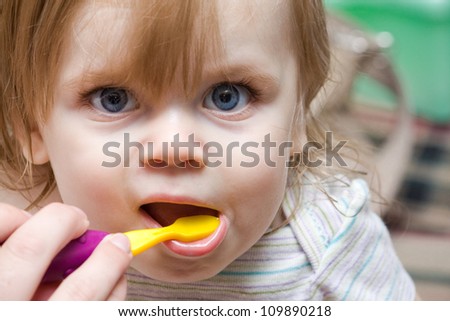 mom helping out a little girl with a toothbrush