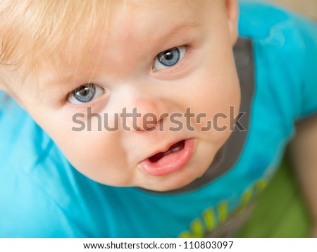 A little toddler boy is making a very sad face up at the camera. depth of field is very shallow and focused on the eyes.