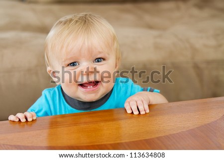 Toddler trying to hold himself up nice and proud at the edge of the table