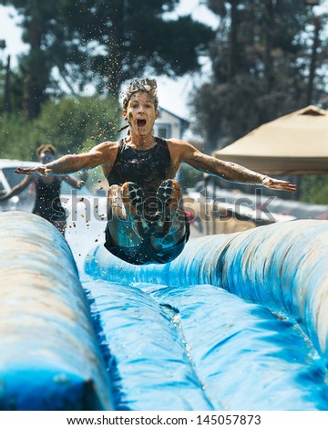 BOISE, IDAHO/USA - AUGUST 25 - Unidentified woman jumps down a slide getting air time. The Dirty Dash on August 25, 2012
