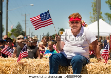 MIDDLETON, IDAHO - JULY 4: Lavena Gardner waving an american flag during the fourth of july parade of 2012 in Middleton, Idaho