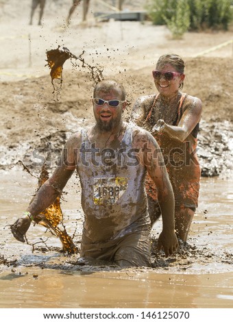 BOISE/IDAHO AUGUST 25: Runners in The Dirty Dash playing in the mud. One runner is splashing her friend. This took took place in Boise, Idaho on August 25, 2012